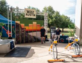 Outdoor, tradeshow-style exhibit hosted by Swift Fit Events with blender bikes, cold plunge and a backdrop that says West Austin.