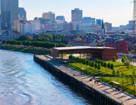 A drone shot of the French Quarter and New Orleans city skyline taken from over the MIssissippi River of the Goldring Woldenberg Riverfront Park at sunset.