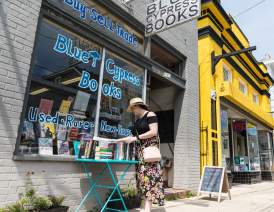 a woman browses the selection of books outside of Blue Cypress Books on Oak Street