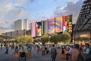 Austin Convention Center rendering shows the outdoor event space with attendees in the foreground looking towards a large screen showcasing ATX Expo 2029 signage on the north side of the building. The Fairmont hotel is in the background and the space includes trees and greenery in front of the building.