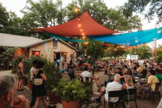 Photo of people sitting on at outdoor patio at Radio Coffee & Beer watching a live band performing on stage.