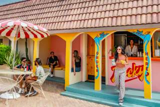 People sitting around an outdoor courtyard with a colorful bar.