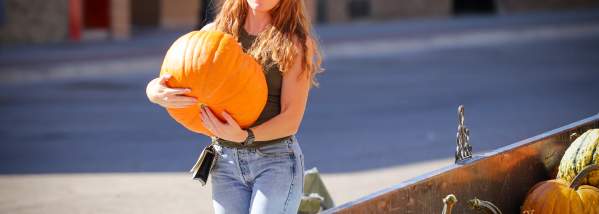 Woman carrying pumpkin during Devils Lake's Fall Festival event.