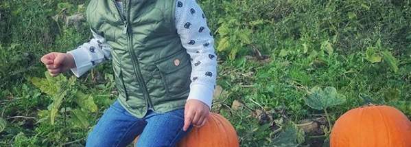 Girl sitting on pumpkins at Katie's Pumpkin Patch
