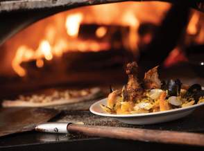 Kaiser Grill Paella dish in front of a pizza oven with fire