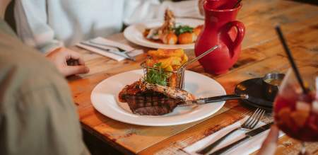 restaurant table with steak dish, drinks and cutlery