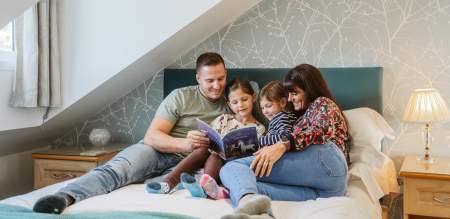 A family in bed reading a children's book