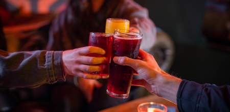 Three people clinking glasses in a dimly lit bar.