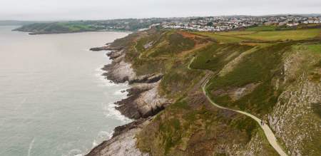 Drone shot of the rugged coastline of Gower with the coast path winding along.