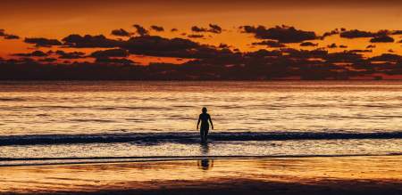 Sunset image of a person swimming at Caswell Bay