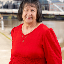 Dawn wearing red dress standing in front of bridge in downtown Rochester
