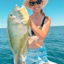 A woman in a boat holding a freshly caught Bluebone fish, in the waters off Port Hedland