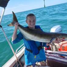 A woman in a boat holding a freshly caught cobia fish, in the waters off Port Hedland