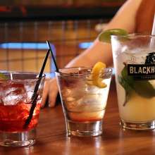 a couple at a bar table with three drinks