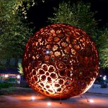 large rosette-patterned sphere in a park at night