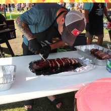 A man cutting a smoked rack of ribs into individual ribs.