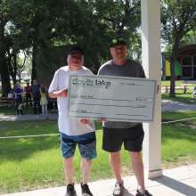 Two men, holding a check for third place at Ribfest.