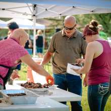 A man serving ribs to a man and a woman.
