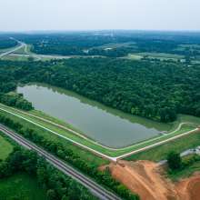 Lake surrounded by greenery and wooded areas, with paved hiking trails at Buffalo Lake in Elizabethtown, Kentucky