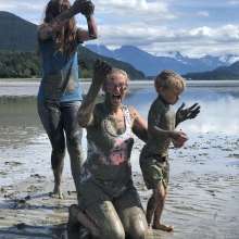 family playing in mud at beach