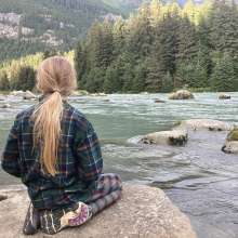 Caught in the tranquility, girl on rock looking at the Chilkoot river