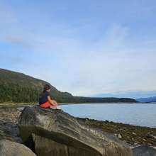 Child sitting on large rock enjoying view at Chilkat State Park