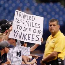 New York Yankees fan holding a sign reading "TRAVELED 1246 MILES TO SEE OUR YANKEES"