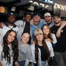 Group of Yankees fans gathered at Yankees stadium posing for a picture