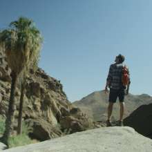 Man standing on bouldin in Palm Canyon.