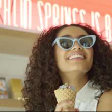 Girl eating ice cream with sunglasses on.