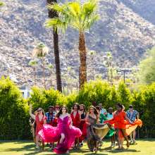 Group of drag queens running on the lawn.