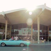 Three people in vintage car in front of PSP.