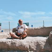 Large couch made of sand with a person sitting on top.