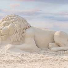 Large sleeping lion sculpture made of sand.