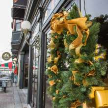 Holiday wreath with gold ribbons hanging on a reflective window