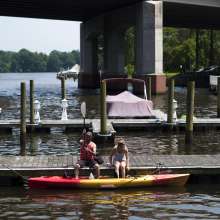Two people on a boardwalk getting ready to get into a kayak