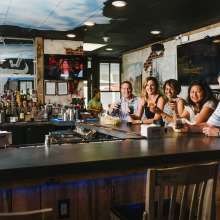 A group of people sitting at a bar smiling