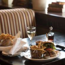Plates of burgers and fries with a glass of wine on a table
