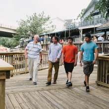 Four men walking along a boardwalk