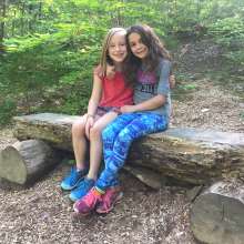 Two girls sitting together on a log