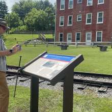 a man taking a photo of the Civil War Trails Marker located at Hanover Junction along the Heritage Rail Trail