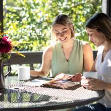 two people sitting on the deck at the Inn at Terra Farms reading a York County PA Travel Guide trying to plan their day