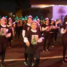 Young girls marching with lit up pink tiaras and green wands to represent the Broadway Musical "Wicked"