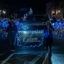 Winner of best performance Glam Dance Studio marching behind their banner down main street all in Blue Christmas Lights