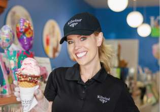 Friendly lady smiling and holding up a waffle cone ice cream.