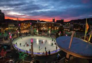People ice skating at Main Street Square in downtown Rapid City, SD surrounded by holiday lights.