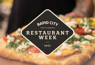 The logo of Restaurant Week 2027 superimposed over a closeup image of a waiter carrying a flatbread pizza.