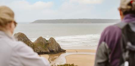 Two people looking out at Three Cliffs Bay