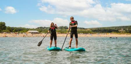 young couple stand up paddle boarding on oxwich bay