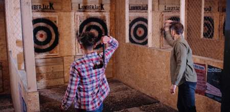 A teen boy and man throwing axes at a target
